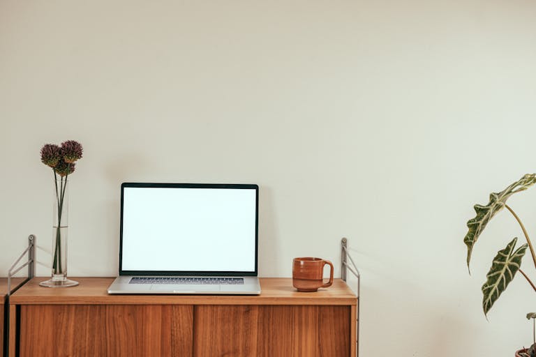 A clean, minimalist workspace with a laptop and coffee mug on a wooden desk for productivity.